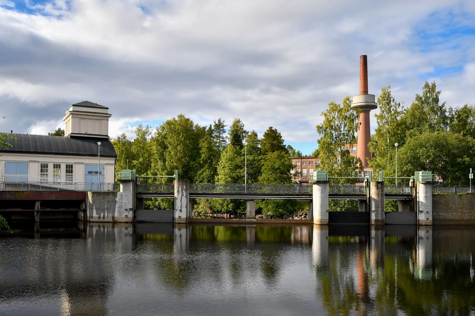 Vesivoimalaitoksen pato ja piippu heijastuvat veteen Jyväskylässä