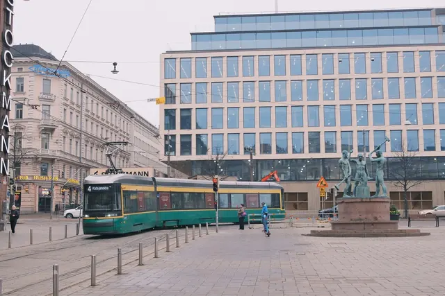 Raitiovaunu kulkee Stockmannin ja veistoksen ohi Helsingin keskustassa